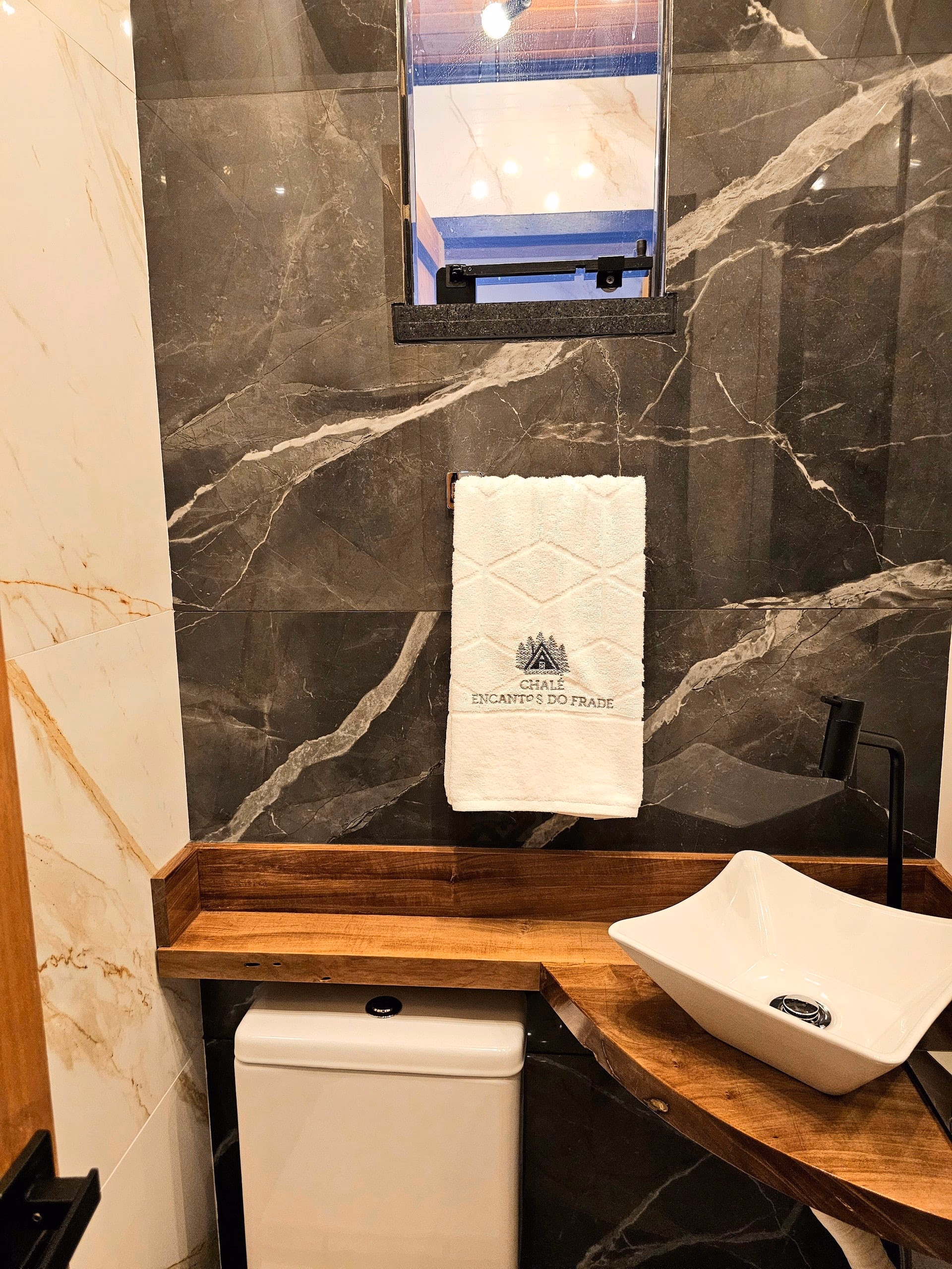 Amenities e bancada de mármore escuro no banheiro