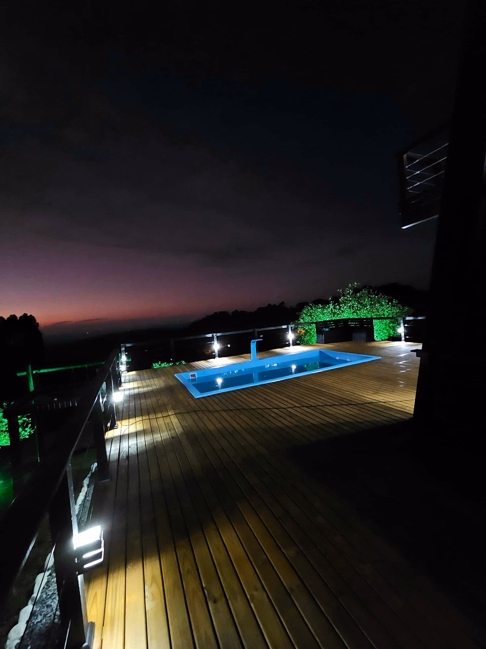 Piscina e deck iluminados à noite, ambiente aconchegante