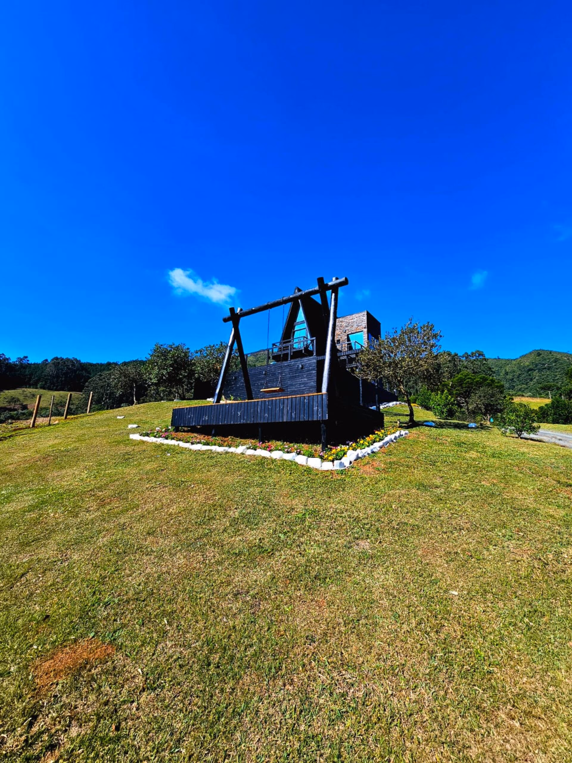 Silhueta do chalé A-frame em preto contra o céu azul intenso