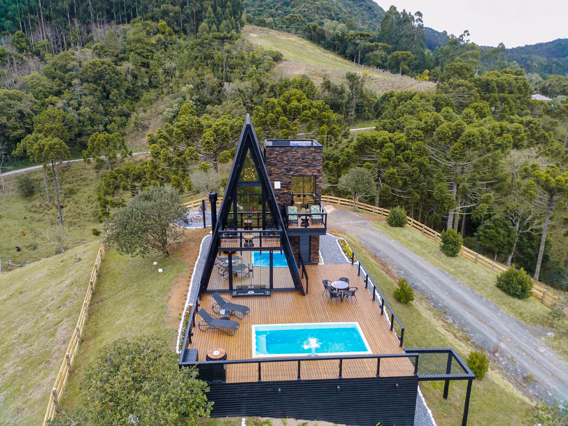 Vista aérea do chalé A-frame em meio à paisagem verde da Serra Catarinense
