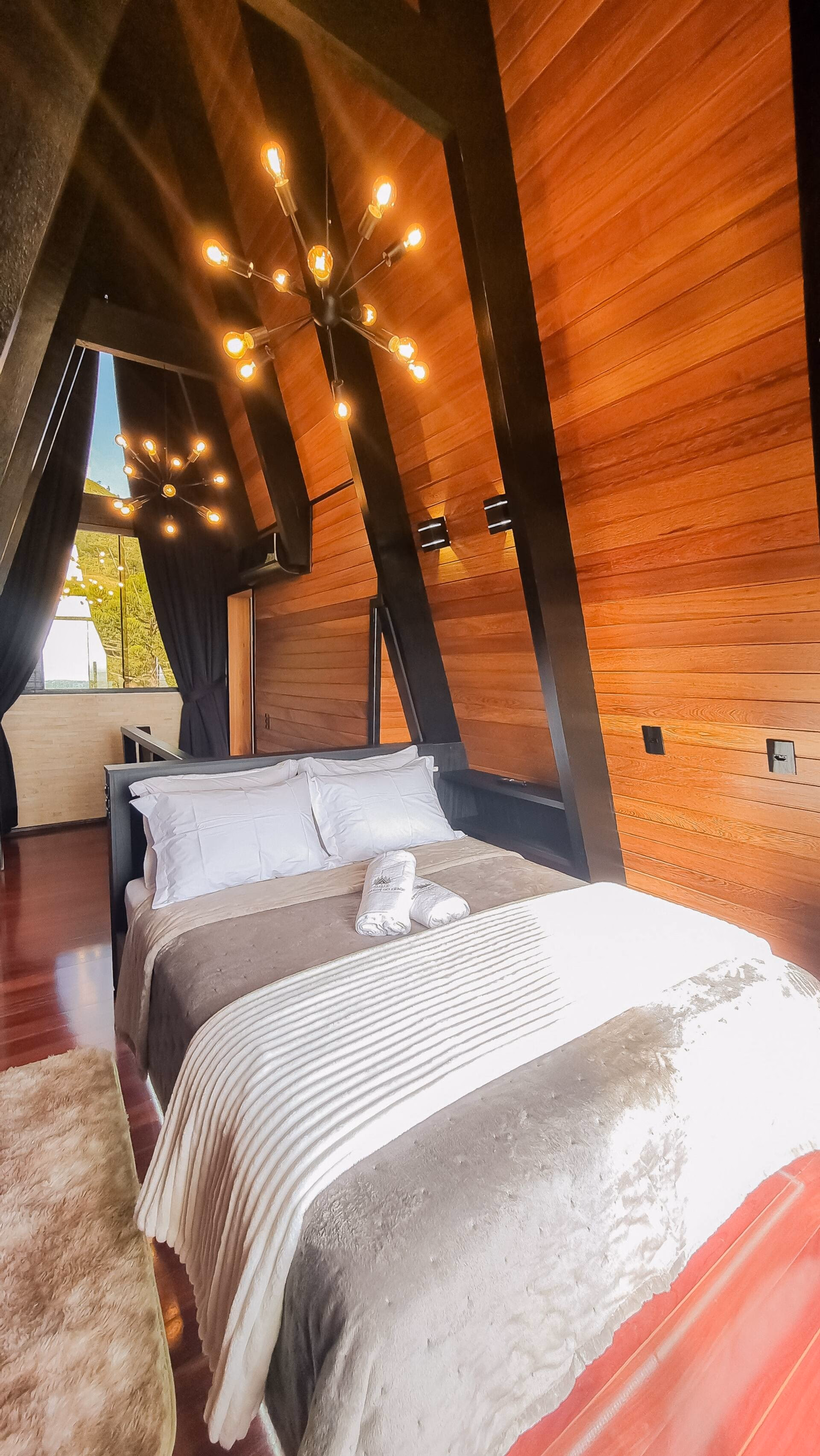 Cama de casal no quarto, iluminada pela luz quente do entardecer