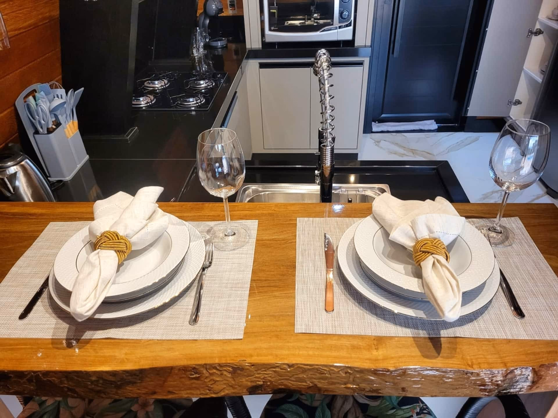 Mesa de jantar posta para duas pessoas, com taças de vinho e guardanapos